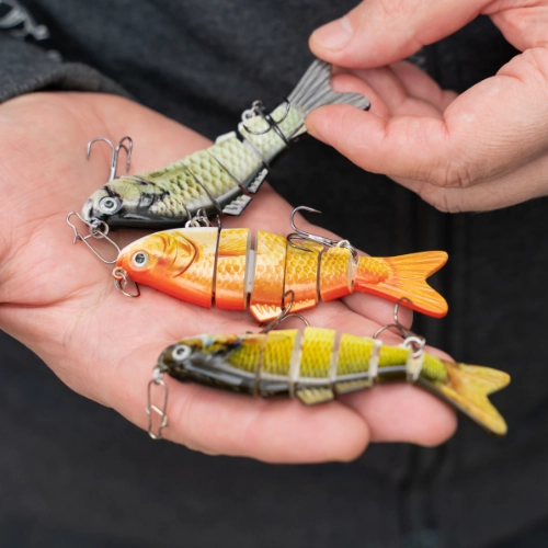 Colourful fishing lures with hooks held in a person’s hand