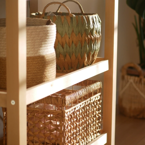 Woven storage baskets displayed on wooden shelving beside a large indoor plant.