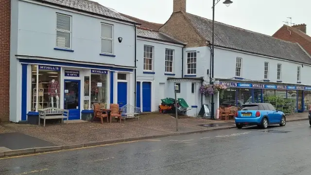 Myhills Pet & Garden shop in Watton with blue storefronts, outdoor furniture and gardening products displayed outside.